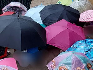 Kinder hocken auf dem Boden und haben viele bunte Regenschirme über sich aufgespannt.