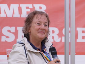 Frau und Mann unter einem Veranstaltungszelt mit Mikrofonen in der Hand.