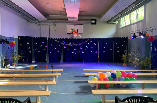 Bunt geschmückte Turnhalle mit vielen Ballons rechts zwischen Turnbänken.