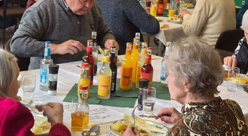 Menschen an Tischen beim Essen, es gibt Spargel und Getränke stehen auf den Tischen. Gemeinsames Mittag.