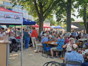 Großes Fest, Draußen, Schattige Bäume und Pavillons unter denen viele ältere Menschen sitzen.