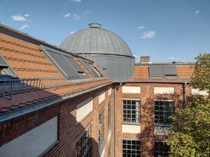 Gebäude. Dach mit Dachfenstern mit Jalousien verschlossen. Eine graue Kuppel.