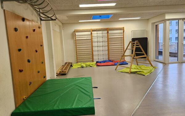Raum mit Kletterelementen. Boulderwand links, Sprossenwand in hintere Bereich des Raums.