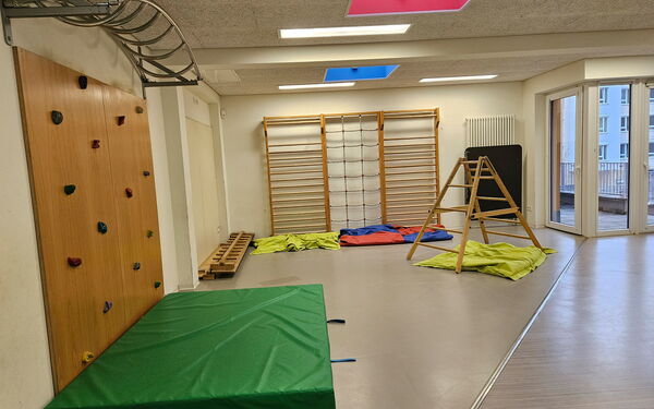 Raum mit Kletterelementen. Boulderwand links, Sprossenwand in hintere Bereich des Raums.