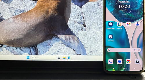 Aufgeklappter Laptop und ein Smartphone an den Bildschirm gelehnt.