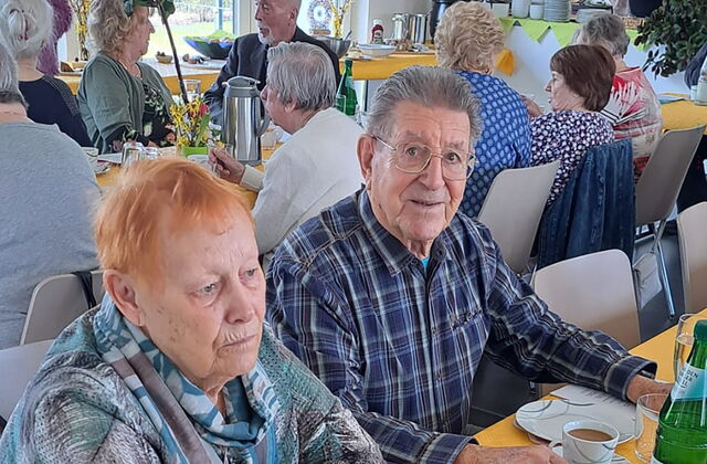 Ältere und alte Menschen sitzen an Tischen und trinken Kaffee.