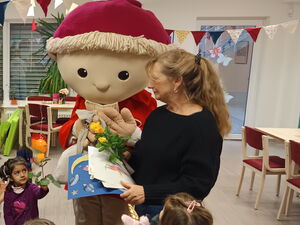 Der Sandmann in Lebensgröße nimmt Karten, Bilder und Blumen zum Geburtstag entgegen. Frau übergibt ihm alles. Kinder stehen um ihn rum.