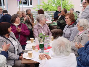 Ältere Menschen an Tischen, leere Teller, leere Kaffeebecher. Sie klatschen der Aufführung.