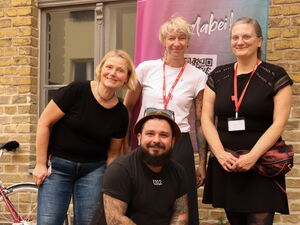 Dynamisches Gruppenbild. 4 Personen in Pose vor Banner der Jugendaktionswoche.
