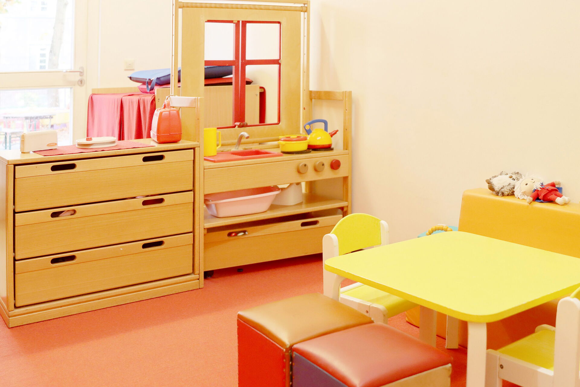 Kinderküche aus Holz, mit Herd, Spüle, Tisch und zwei Stühle.