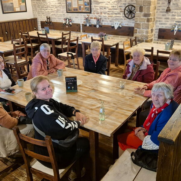 Sonst leeres Restaurant, ein Tisch mit 8 Frauen besetzt. Einige lächeln in die Kamera.