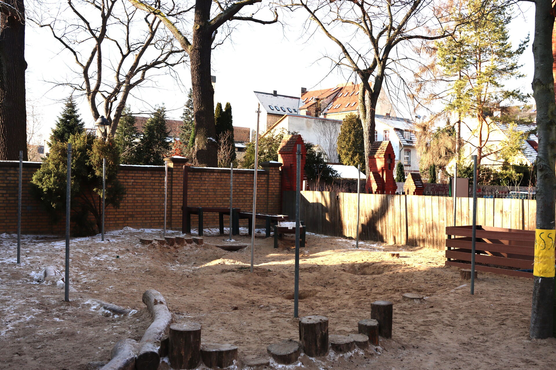 Es ist Winter. Raureif und etwas Schnee auf dem Spielplatz der Kita. In der hinteren Ecke des eingezäunten Geländes ist ein Wasserspeilplatz.