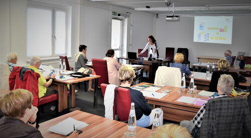 Seminarraum. Menschen an Tischen. Wie in einem Klassenzimmer. Menschen sitzen an Tischen, machen Notizen.