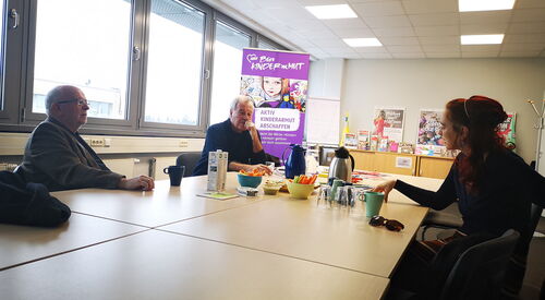 3 Personen an einem Tisch sitzend im Gespräch
