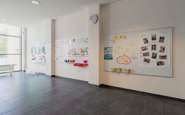 Großes Zimmer, drei große Magnettafeln an der Wand, Gelbe Smileys, eine Foto-Collage und Bilder sind an die Magnetwände geheftet.