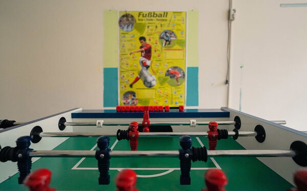 Tischkicker und ein Fußball-Plakat an der Wand.