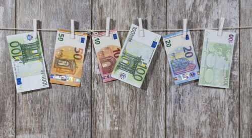 Geldscheine hängen an einer Leine mit Wäscheklammern befestigt. 10 Euro bis 100 Euro Scheine.