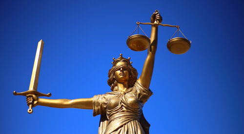 Justicia Skulptur. Weiblich mit Wage in der linken Hand, Schwert in der rechten Hand und Augenbinde.
