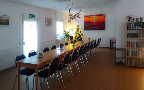 großer Raum, lange Tafel mit vielen Stühlen.