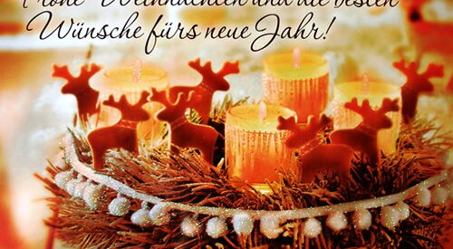 Weihnachtskarte Bild: Gesteck mit 4 Kerzen, kleinen Rentieren und Tannenzweigen im warmen gelben Licht. Text: Frohe Weihnachten und die besten Wünsche fürs neue Jahr!