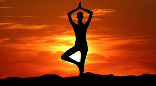Eine Frau in Yoga-Pose vor dem Sonnenaufgang