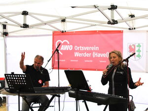 Mann und Frau an 2 Keyboards und Mikrofonständern singen.