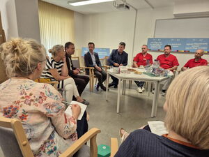 Raum, Stuhlkreis in der Mitte ein Tisch mit Getränken und Snacks.