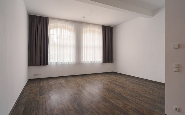 Leeres großes Zimmer / 1-Raum-Wohnung mir großen Fenstern mit Vorhängen.