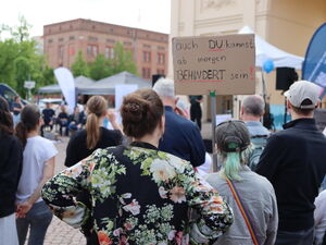 Menschen von hinten. Eine Person hält Protestschild hoch. Darauf steht: auch du kannst ab morgen behindert sein!
