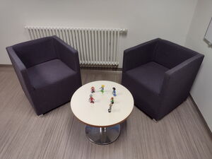 Ein Raum mit einem runden Tisch und zwei schwarzen Sesseln.