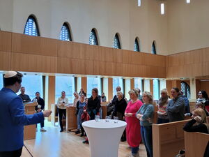 Blick in die Synagoge in die Gruppe der Teilnehmenden. Großer hoher Raum, mit vielen Fenstern.