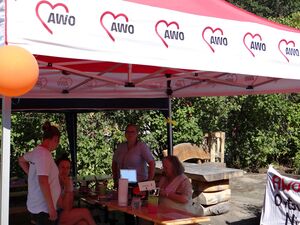 AWO Pavillon. 2 Frauen sitzen an einer Biertischgarnitur, zwei weite stehen. Sie tragen sommerliche Kleidung.