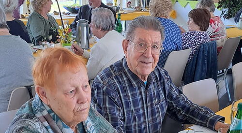 Ältere und alte Menschen sitzen an Tischen und trinken Kaffee.