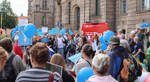 Protest. Viele Menschen vor dem Potsdamer Rathaus. Viele mit blauen Luftballons vom SEKIZ und viele recken ihre Protest Schilder nach oben.