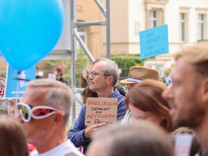 Menschen mit Schildern und blauen Luftballons von SEKIZ. Ein Mann mit Brille und grauen Haaren hält sein Prodestschild in Richtung Kamera. Text: Inklusion braucht ein Netzwerk in Potsdam.