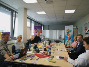 Konferenzraum im Büro Kinder(ar)mut. 8 Personen sitzen am Tisch.