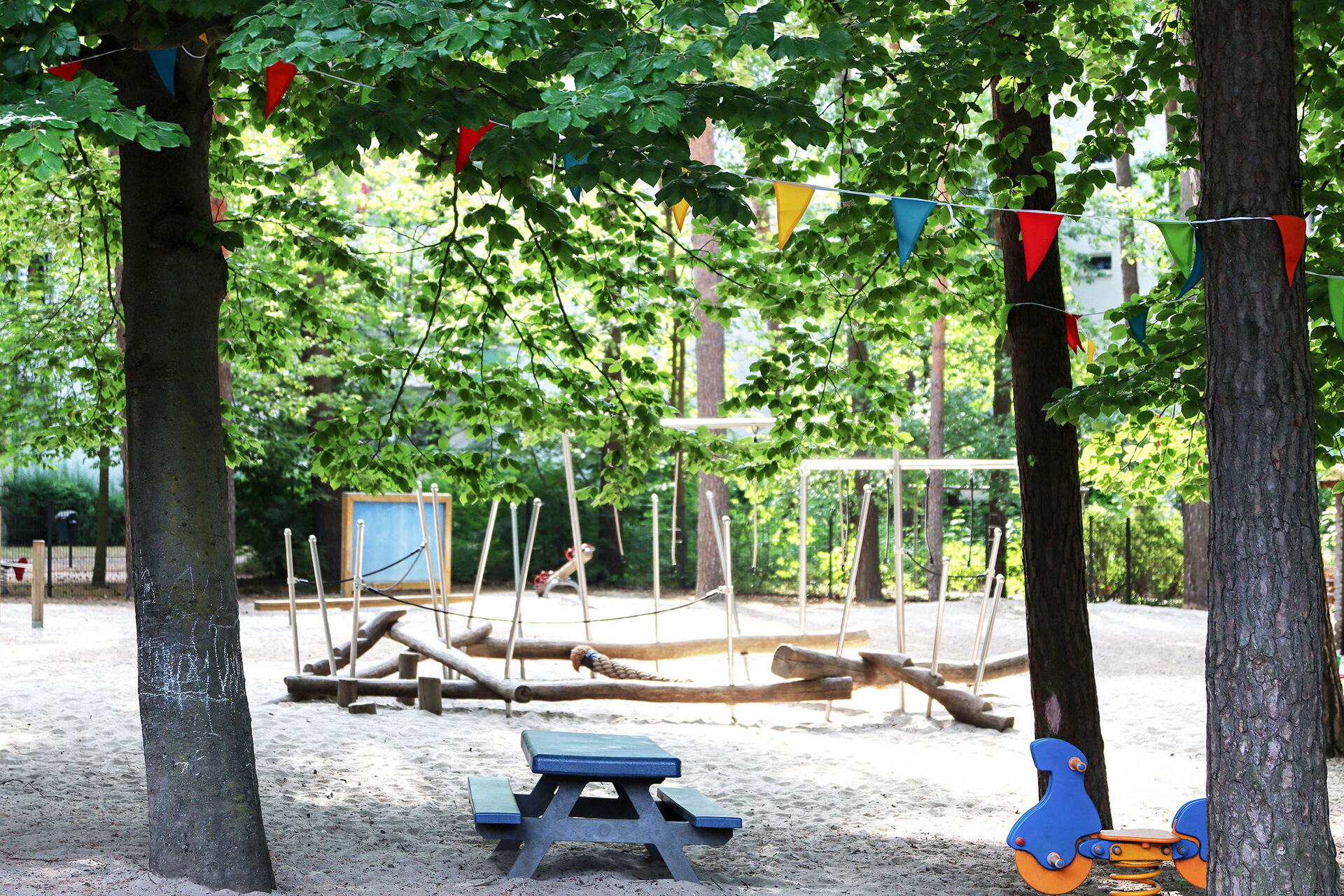 Spielplatz zwischen Bäumen. Gerüst zum Balancieren aus Holzstämmen, Schaukeln, Wippe.