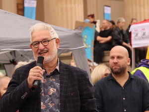 Viele Menschen vor der Nikolaikirche. Ein Mann mit weißen Haaren, Bart und Brille spricht in ein Mikrofon.