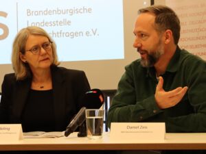 Brandenburgischen Landesstelle für Suchtfragen -Geschäftsführerin Andrea Hardeling und Daniel Zeis sitzen am Tisch. Auf dem Tisch sind Namensschilder.
