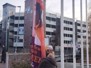 Zwei Frauen hissen eine Flagge zum Orange Day.