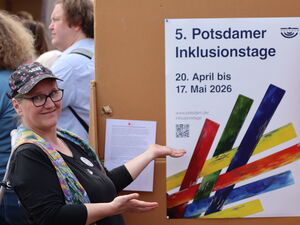 Frau weißt auf ein Plakat der 5. Potsdamer Inklusionstage.