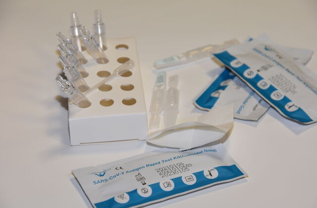 Drei verpackte Corona Tests. Ampullen in einem Pappständer
