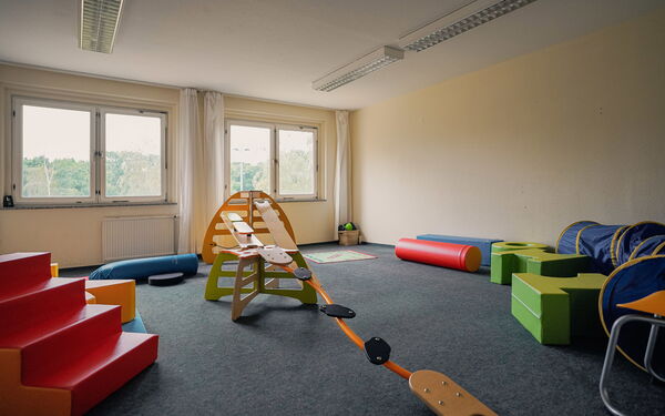 Großes Spielzimmer mit Geräten zum Balancieren und Kletter, eine rote Treppe.
