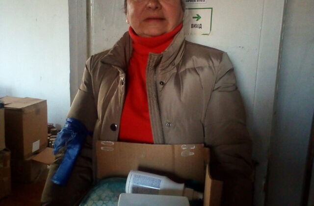 Eine Frau mit einem Karton mit Sachspenden in der Hand