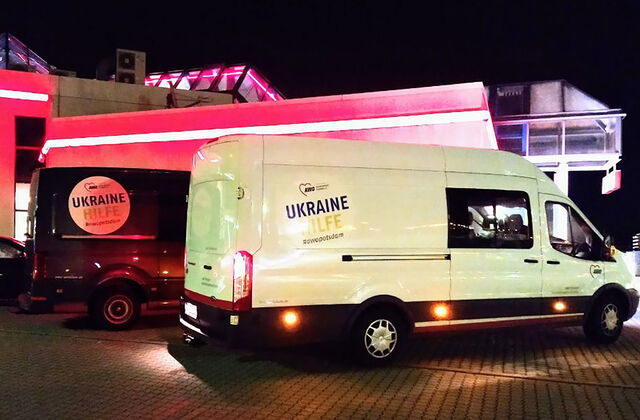 Zwei große Transporter mit Aufdruck "Ukrainehilfe" stehen auf einem Parkplatz bei Nacht.