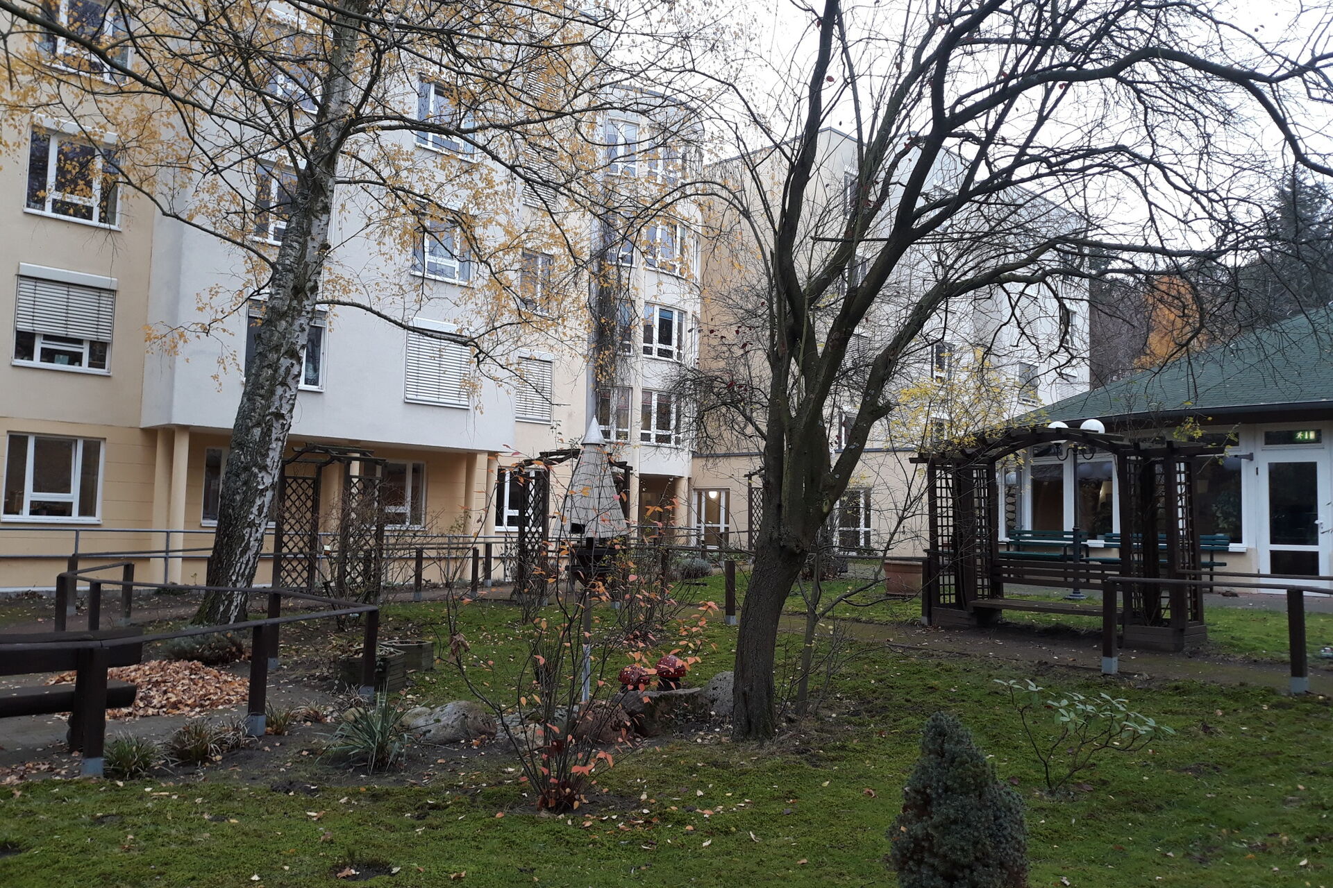 Wohnhause mit einer Wiese davor. Kahle Bäume und Sträucher.