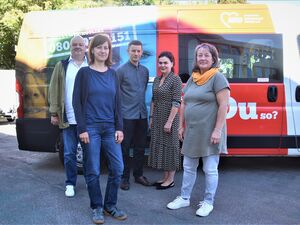 5 Personen vor einem Transporter der bunt mit mit AWO Bild bedruckt ist. 2 Männer, 3 Frauen. Die Sonne scheint.