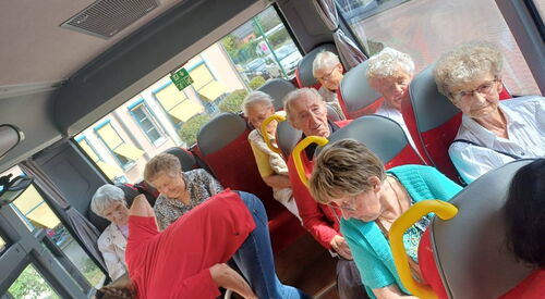 Senioren in einem Bus sitzend.