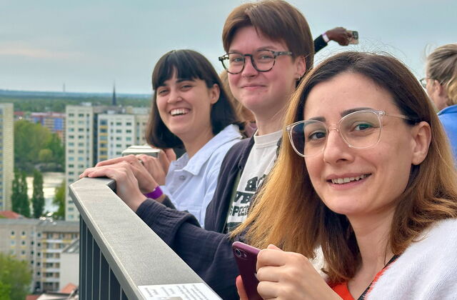 3 Frauen am Geländer einer Aussichtsplattform. Sie lächeln in die Kamera.