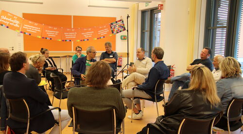 14 Personen sitzen in zwei Kreisen auf Stühlen. Im inneren Kreis wird diskutiert.
